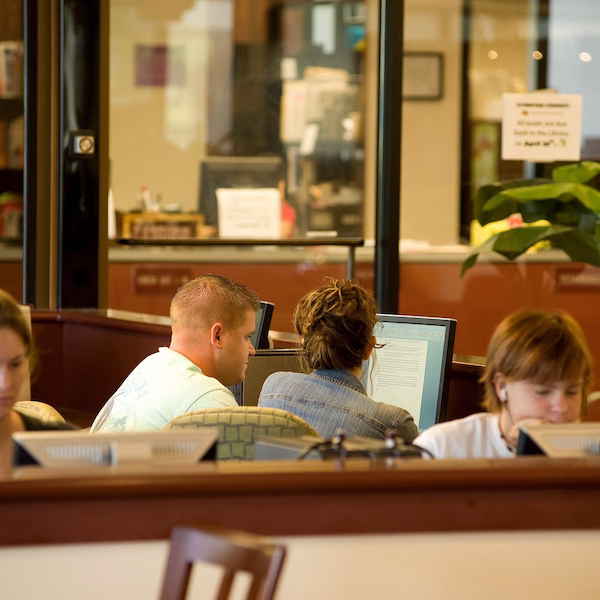 Students working on computers in front of cafe glass