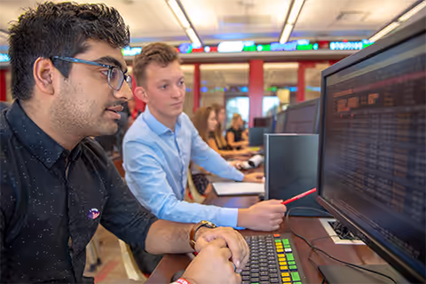 students in trading room look at monitors