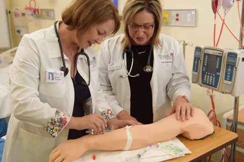 Nursing student practicing on task trainer arm model
