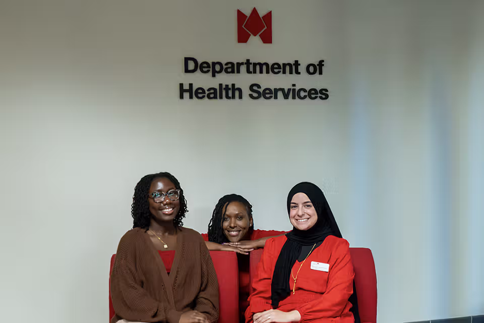 Department of Health Services staff in front of department sign