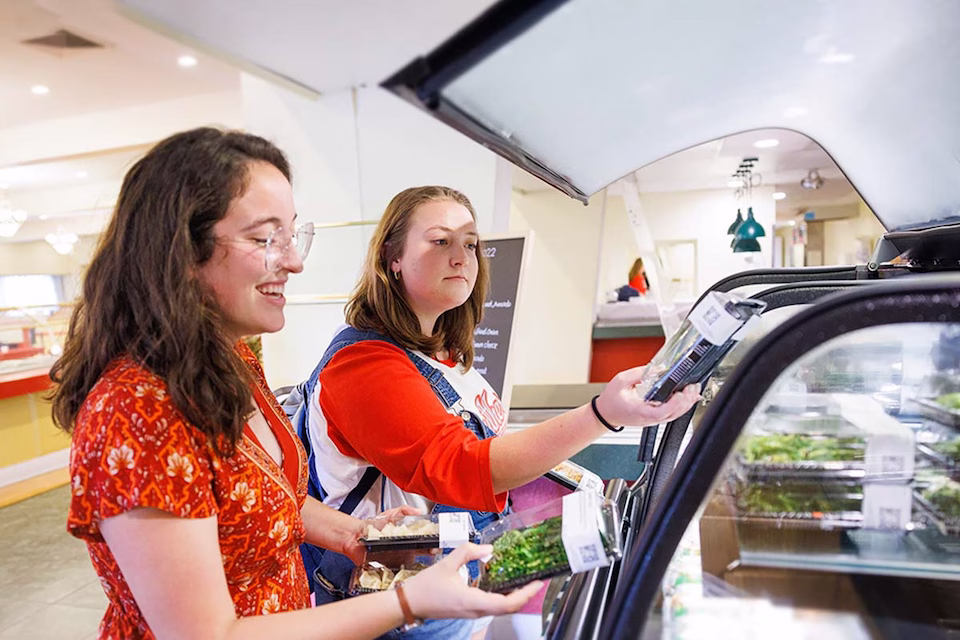 Students selecting salads from glass food service case