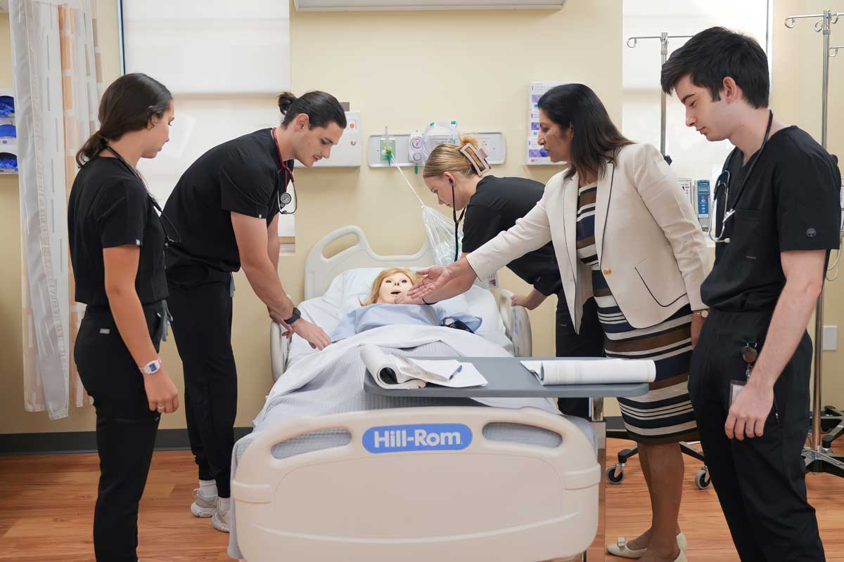 Joseph and students at hospital bed with nursing dummy