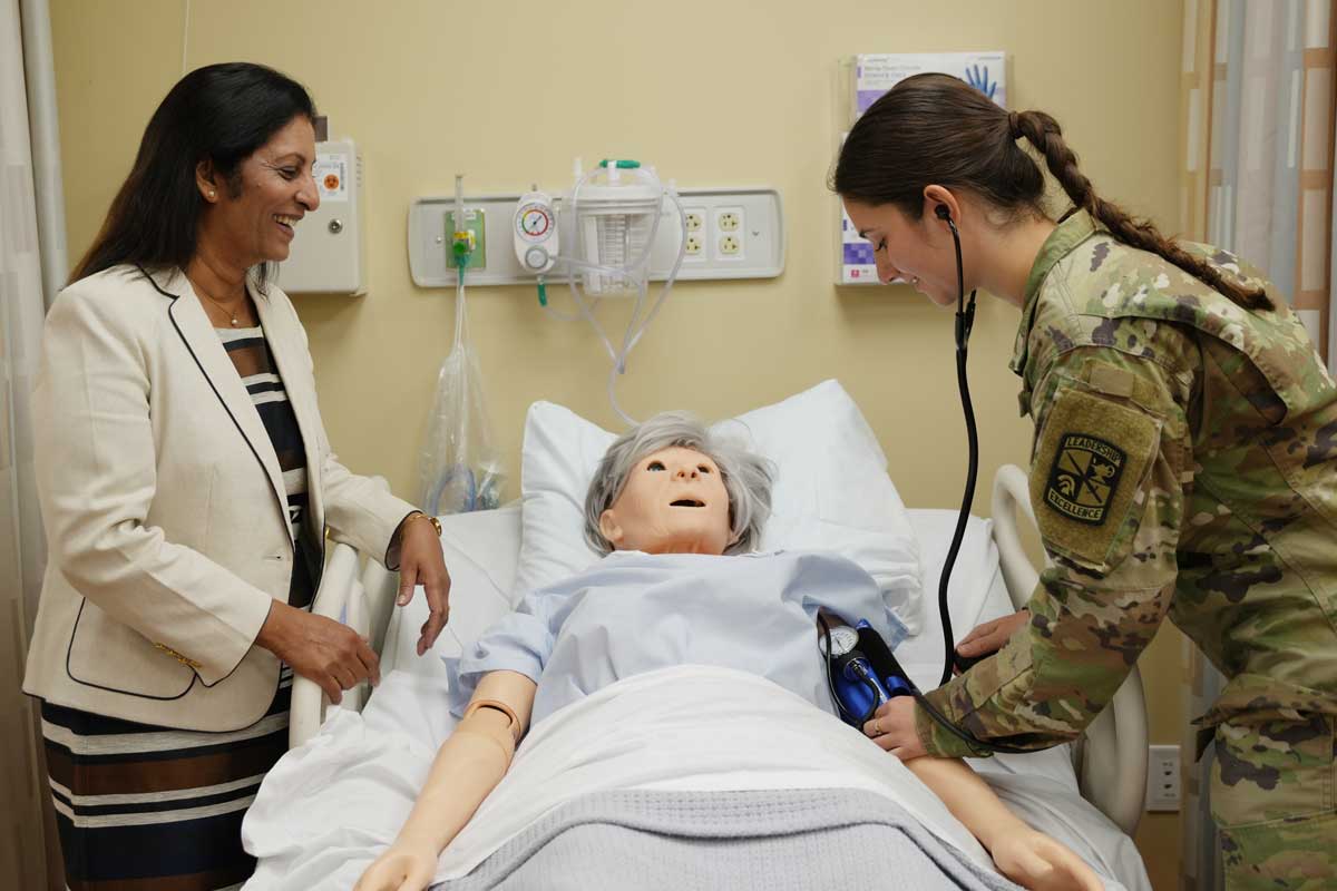 Katherine working with a nursing dummy in a hospital bed. 