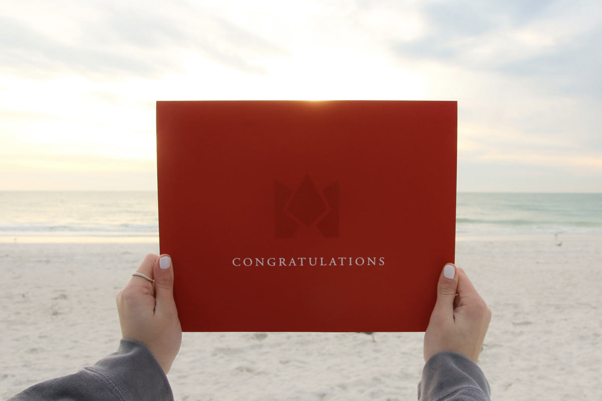 hands holding an FSC acceptance packets on the beach