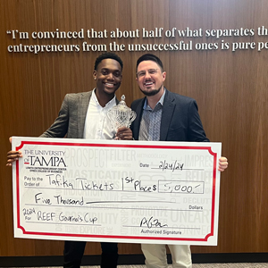 Kuanda standing with a large check