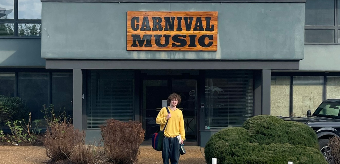 zach in front of Carnival Music sign