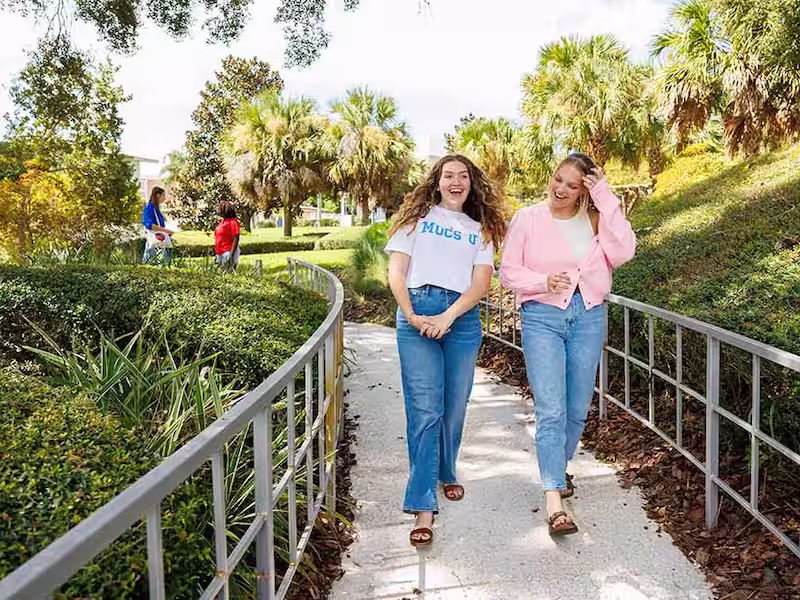 two women walking through Lynn's garden on campus
