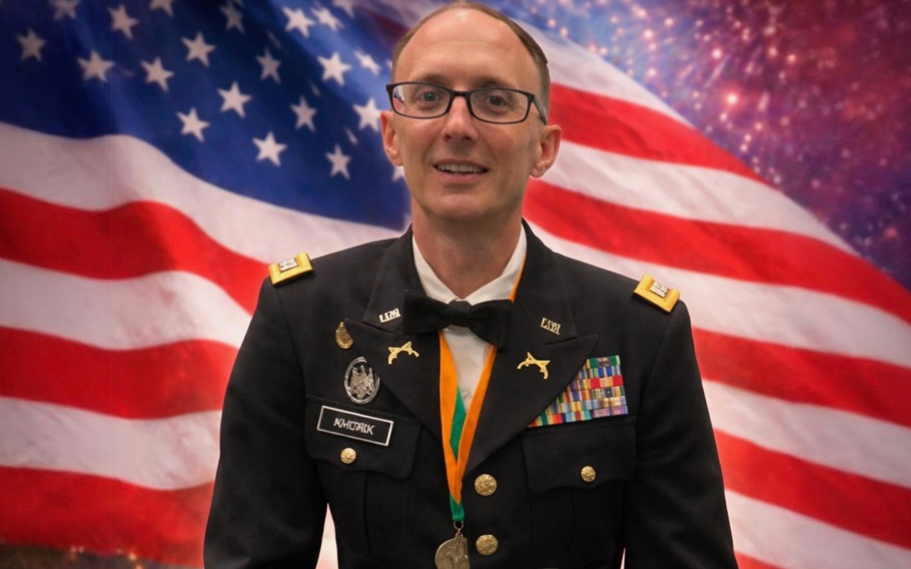 Khork standing in front of an American flag in uniform